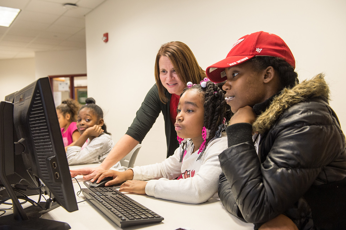 Woman at computer with two 4th grade students